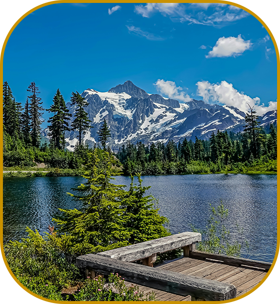 A dock on the shore of a lake with mountains in the background.